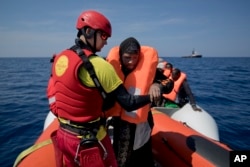 FILE - Proactiva Open Arms lifeguard Ivan Martinez, from Spain, rescues migrants from a rubber boat sailing out of control, in the Mediterranean Sea, about 56 miles north of Sabratha, Libya, April 6, 2017.