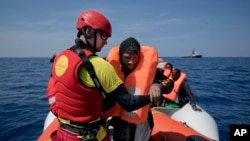FILE - Proactiva Open Arms lifeguard Ivan Martinez, from Spain, rescues migrants from a rubber boat sailing out of control, in the Mediterranean Sea, about 56 miles north of Sabratha, Libya, April 6, 2017. Spain's maritime rescue service says it rescued 48 people Thursday from a boat in the Mediterranean Sea, halfway between Spain and Morocco.