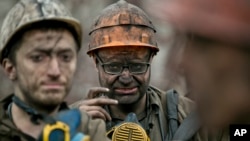 Ukrainian coal miners wait for a bus after exiting the underground of the Zasyadko mine in Donetsk, Ukraine, March 4, 2015.