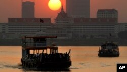 FILE - Ferries transport villagers, students and civil servants from Phnom Penh to Arey Ksat across the Mekong River as the sun sets in Phnom Penh, Cambodia, Saturday, Jan. 31, 2015. (AP Photo/Heng Sinith)