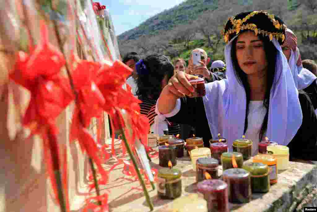 A Yazidi woman lights candles during a ceremony at Lilash Temple to commemorate the death of women who were killed by Islamic State militants, during the International Women Day, in Shikhan north of Iraq, March 8, 2019.