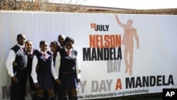 A group of schoolchildren pose near a banner announcing Mandela Day at the Nelson Mandela Foundation in Johannesburg, July 17, 2011