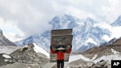 In this March 7, 2016 photo, a porter fetches the ladders for the icefall doctors who will be fixing the route for the climbers trying to attempt the summit of Mt Everest this year at Everest Base Camp in Nepal.