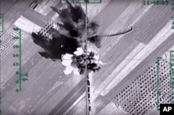 In this photo made from the footage taken from Russian Defense Ministry official web site, Feb. 1, 2016, an aerial image shows what it says is a column of heavy trucks carrying ammunition hit by a Russian air strike near Aleppo, Syria.