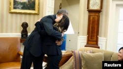 پرزیدنت اوباما نینا پم پرستار دالاسی را درآغوش می کشد. دیان مادر او به صحنه نگاه می کند. کاخ سفید، واشنگتن، ۲۴ اکتبر ۲۰۱۴ 
