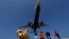 FILE - Tourists take pictures at Mai Khao Beach, as a plane approaches the Phuket International Airport in Phuket, Thailand March 17, 2016. 