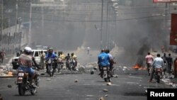 Haitians pass through a barricade on a street in Port-au-Prince, Haiti, July 8, 2018.
