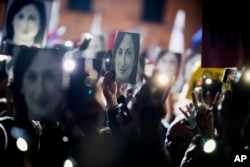 FILE - People hold pictures of slain journalist Daphne Caruana Galizia as they protest, in Valletta, Malta, Nov. 29, 2019.