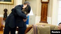 President Barack Obama hugs Dallas nurse Nina Pham as her mother Diane looks on, Oval Office, Washington, Oct. 24, 2014.