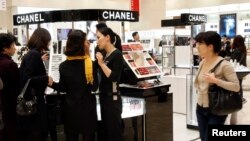 Customers choose cosmetics at a cosmetics counter at the Shinsegae department store in Seoul.