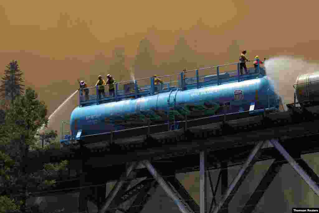 미국 캘리포니아즈 플루머스 국유림에서 발생한 산불을 진압하기 위해 소방관들이 기차 물탱크에서 물을 뿌리고 있다.