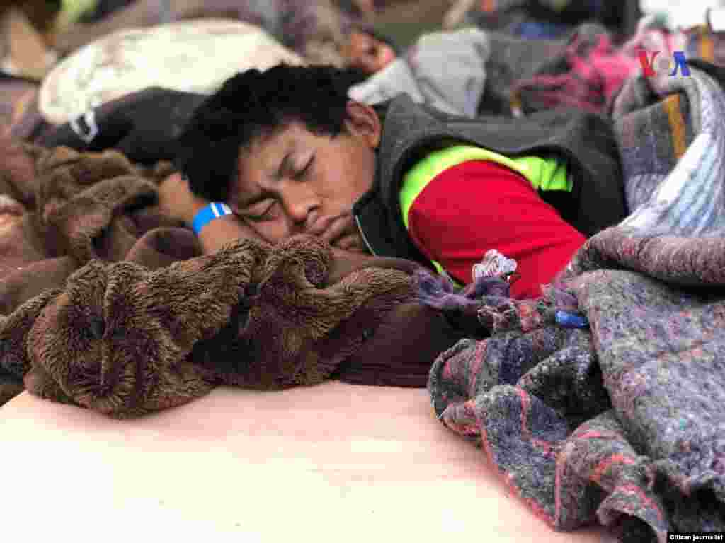 Una persona duerme sobre unas cobijas en el piso, en un albergue en México.&nbsp; Fotografía: Celia Mendoza- VOA