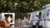 Postal workers load packages in their mail delivery vehicles in the Panorama City section of Los Angeles, California, Aug. 20, 2020.