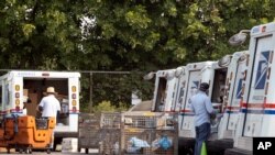 Postal workers load packages in their mail delivery vehicles in the Panorama City section of Los Angeles, California, Aug. 20, 2020.