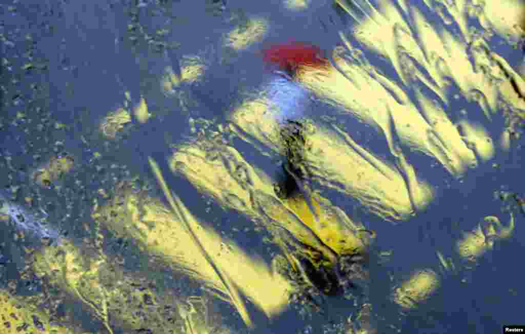 A man seen through a wet window crosses a road in Colombo, Sri Lanka. 