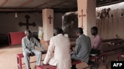 FILE - The Rev. Yousef Zamgila, left, a Lutheran pastor, speaks to members of his congregation at the improvised church they helped set up in Omdurman, Khartoum’s twin city, Aug. 22, 2019. 