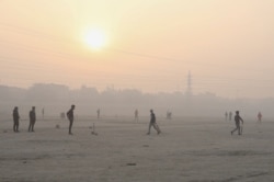 People play cricket on the floodplains of the Yamuna river on a smoggy morning in New Delhi, India, Nov. 17, 2021.