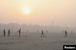 People play cricket on the floodplains of the Yamuna river on a smoggy morning in New Delhi, India, Nov. 17, 2021.