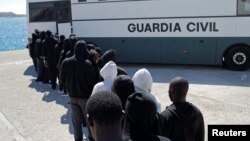 Migrants intercepted aboard a dinghy off the coast in the Strait of Gibraltar, are led into a bus of Spanish civil guard after arriving on a rescue boat at the port of Tarifa, southern Spain, June 29, 2018. 