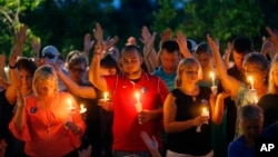 People hold up their hands in prayer during a candlelight vigil for fallen Baton Rouge police officers at the Healing Place Church in Baton Rouge, Monday, July 18, 2016.
