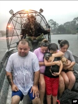 FILE - In this photo provided by the Texas Parks &amp; Wildlife Department, a family is rescued via fan boat by a member of the department from the floodwaters of Tropical Depression Imelda near Beaumont, Texas, Sept. 19, 2019.