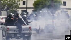 En esta imagen de archivo, del 28 de mayo de 2018, policías con equipo antimotines, montados en la parte trasera de camionetas, disparan a estudiantes que protestaban contra el presidente de Nicaragua, Daniel Ortega, en Managua. (Foto AP/Esteban Félix, archivo)