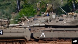 Israeli soldiers work next to their tanks near the Israel Gaza border, Israel, Tuesday, March 26, 2019.