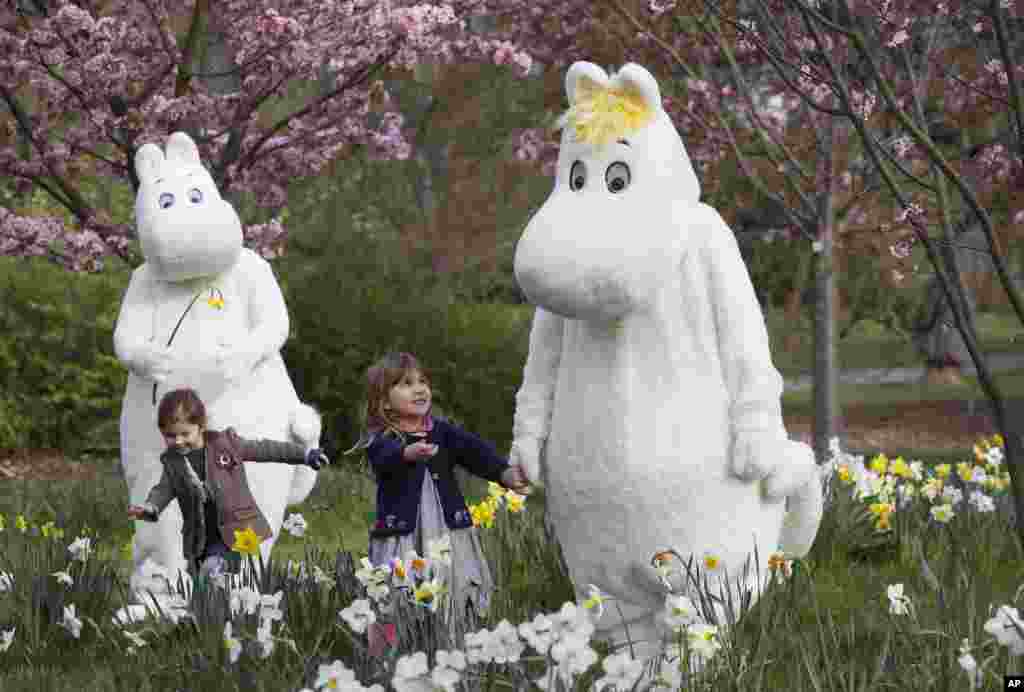 Sofia Lopez, right, and Eve Chick, both three years old, meet Moominmamma, right, and Moomintroll, left, at Kew Gardens Easter Festival at Royal Botanic Gardens, Kew in London.