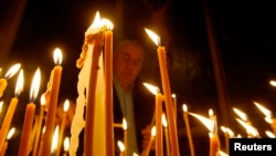 FILE - A man lights candles during a religious service marking the anniversary of mass killings of Armenians in Ottoman Empire in 1915 at an Armenian church in Tbilisi, Georgia.