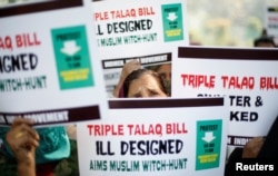 FILE - Muslim women hold placards during a protest against a bill passed by India's lower house of Parliament last week that aims at prosecuting Muslim men who divorce their wives through the "triple talaq," or instant divorce, in New Delhi, Jan. 4, 2018.