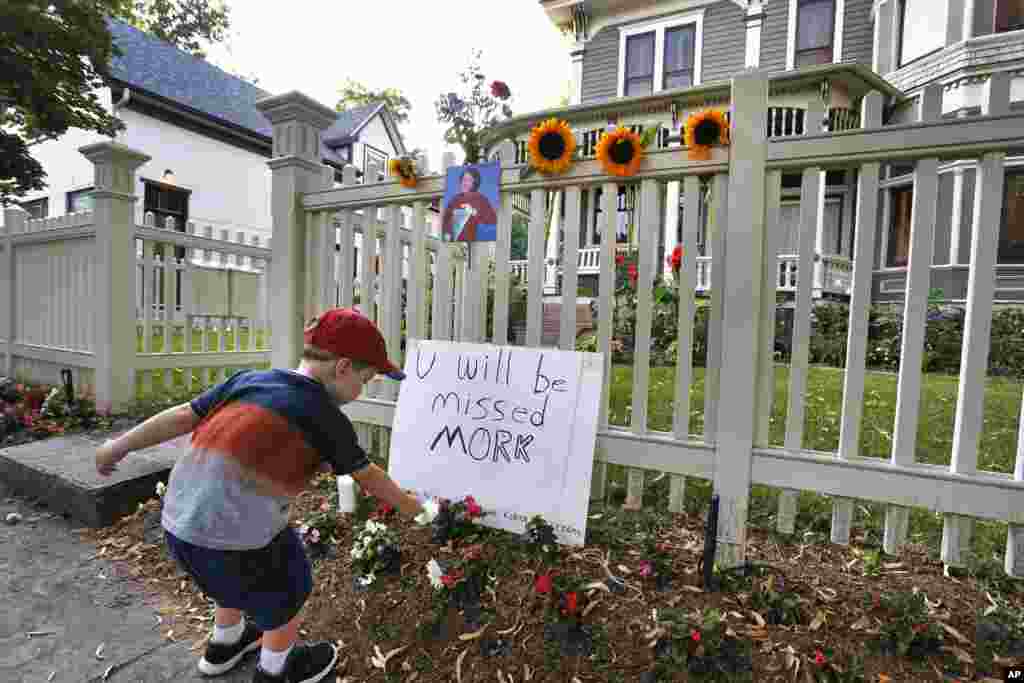 AJ Polis leaves a flower alongside a placard and a photo of the late actor Robin Williams as Mork from Ork, as people pay their respects at the home where the 1980's TV series "Mork & Mindy", was set, in Boulder, Colorado, Aug. 11, 2014.