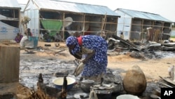 A woman salvages cooking pots at the site of an explosion in Maiduguri, Nigeria, June 8, 2017. Authorities in northeast Nigeria say at least 14 people are dead and dozens are wounded after Boko Haram militants launched a series of attacks.