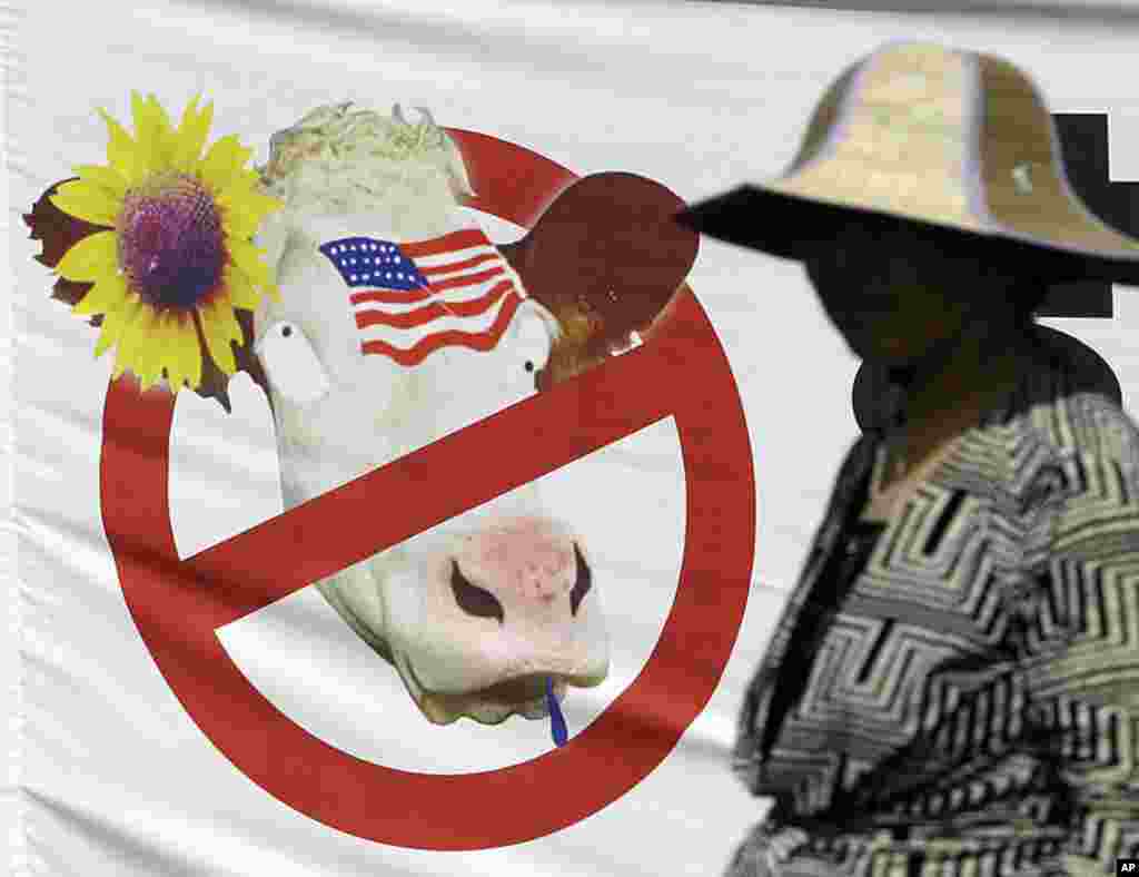 A woman walks past a picture of U.S. import beef during a May Day rally in downtown Seoul, South Korea, May 1, 2012.