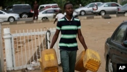 Un homme porte des bidons d'essence à Abuja, Nigeria, le 26 mai 2015.