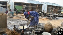 A woman salvages cooking pots at the site of an explosion in Maiduguri, Nigeria, June 8, 2017. Authorities in northeast Nigeria say at least 14 people are dead and dozens are wounded after Boko Haram militants launched a series of attacks.