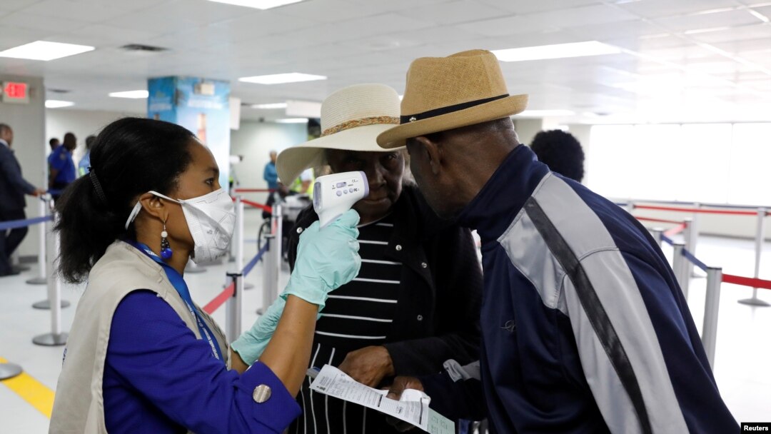 Travelers arriving into Haiti at the International Airport Toussaint Louverture get their temperature checked by a worker of the Haitian Public Health and Population Ministry (MSPP).