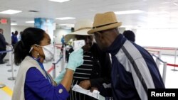 Travelers arriving into Haiti at the International Airport Toussaint Louverture get their temperature checked by a worker of the Haitian Public Health and Population Ministry (MSPP).