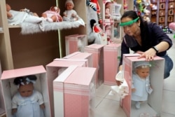 A woman disinfects merchandise at a doll store which reopened for business amid the coronavirus disease (COVID-19) outbreak in Madrid, Spain, May 19, 2020.