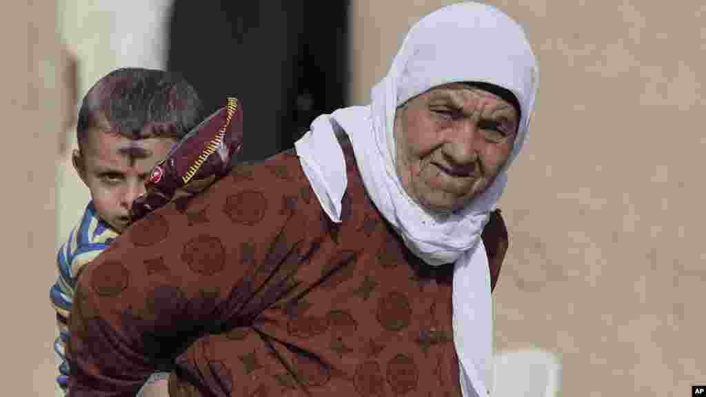 Kurdish people stand in Mursitpinar on the outskirts of Suruc, at the Turkey-Syria border, while fighting continues between Syrian Kurds and the militants of Islamic State group just across the border in Kobani, Syria, Oct. 18, 2014. 