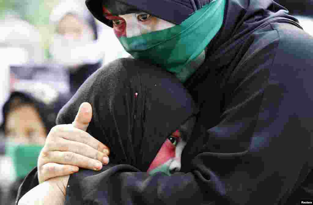 A Filipino Muslim woman, with colors of Palestinian flag painted on her face, cries as she embraces her child during a rally held by the Anak Mindanao (Children of Mindanao) Party List group outside the Israeli embassy in Taguig, Metro Manila, Philippines.