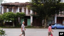 Papan residents strolling past a row of pre-war shop houses that are now mainly abandoned.