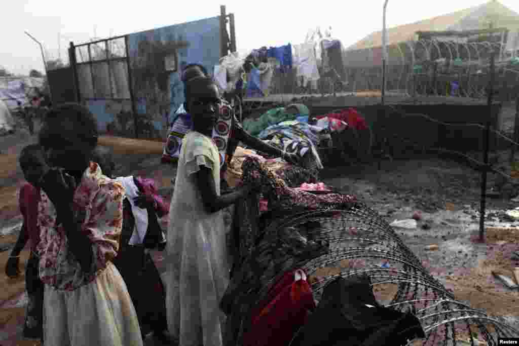 Meninas sul-sudanesas recolhem as suas roupas estendidas no arame farpado do campo de refugiados da&nbsp; UNMISS em Tongping, Juba, Sudão do Sul, Fev. 19, 2014.&nbsp;