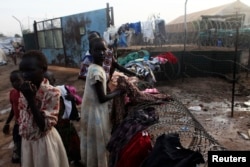 South Sudanese girls displaced by the fighting collect their laundry from a barbed wire in a camp for displaced persons in the UNMISS compound in Tongping in Juba, Feb. 19, 2014.