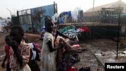 FILE - South Sudanese girls displaced by the fighting collect their laundry from a barbed wire in a camp for displaced persons in Juba, Feb. 19, 2014. 