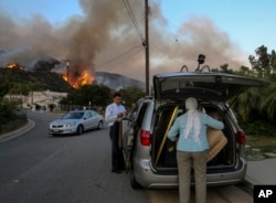 Residents evacuate their home as a wildfire is burning along a hillside in Duarte, California, June 20, 2016.