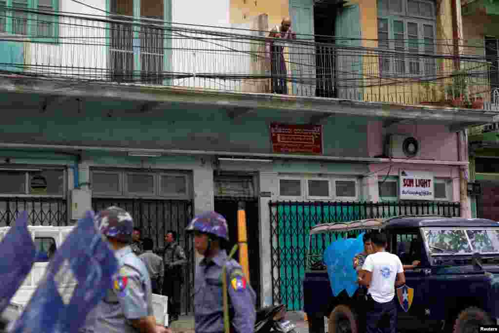 A Muslim looks down from the balcony of his home as police officers stand guard in Mandalay, Myanmar, July 3, 2014.