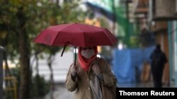 Iranian woman wearing a protective face mask, walks on the street, as government imposed a full lockdown, amid the spread of the coronavirus disease (COVID-19), in Tehran