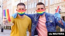 Gay couple Dawid Mycek and Jakub Kwiecinski pose with the rainbow-patterned face masks on a street in Gdansk, Poland, April 8, 2020. 