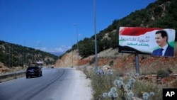 In this Friday, July 20, 2018, photo, a poster of President Bashar Assad with Arabic that reads "Welcome in victorious Syria." is seen on the border between Lebanon and Syria. 