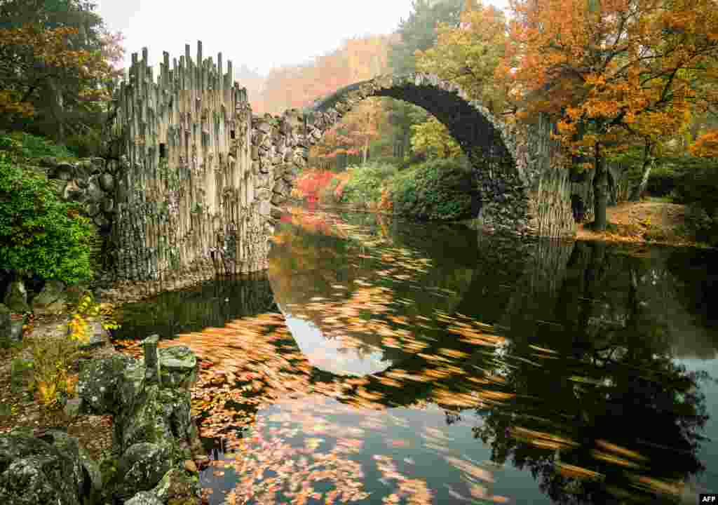 Fog hangs over trees in autumnal colors and the Rakotzbruecke bridge of the Rhododendronpark Kromlau landscaped park in Kromlau, eastern Germany, Oct. 27, 2015.